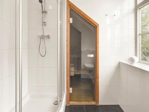 a bathroom with a shower with a glass door at Bungalow by Water near Rotterdam with Sauna in Simonshaven