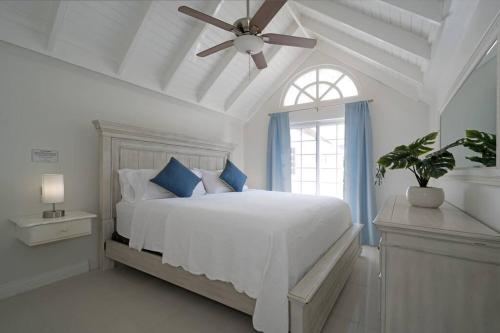 a white bedroom with a bed with a ceiling fan at Marriott SeaCastles F32, Montego Bay in Montego Bay