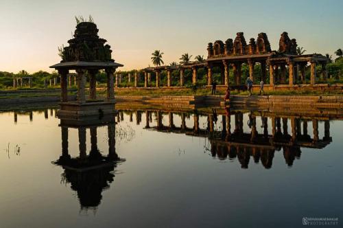 eine Spiegelung eines Gebäudes in einem Gewässer in der Unterkunft Khushi's Paradise Villa hampi in Hampi