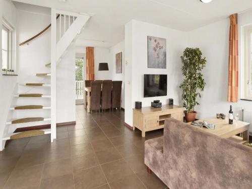 a living room with a couch and a tv at Bungalow by Water near Rotterdam with Sauna in Simonshaven