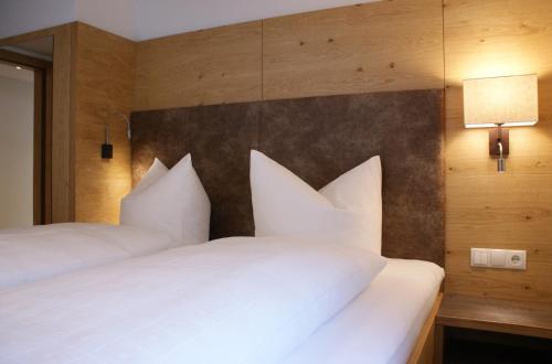 two beds in a hotel room with white pillows at Apart Auhof in See