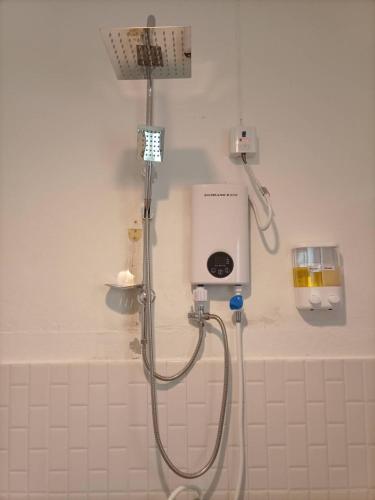 a shower in a white tiled bathroom with a shower at Khaolak Banana Bungalow in Khao Lak