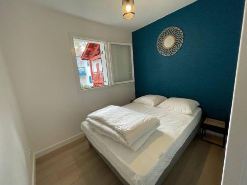 a small bed in a room with a blue wall at Cambo-les-Bains T2 avec piscine et WiFi, cosy pour 2 personnes - FR-1-495-143 in Cambo-les-Bains