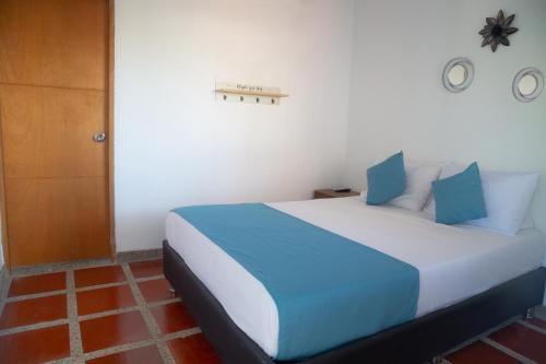 a bedroom with a bed with blue and white pillows at Palaa Mujuii Hotel in Dibulla