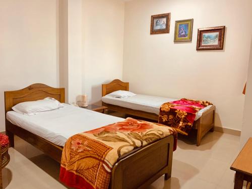 a room with two beds and a table in it at Hotel Devika in Dibrugarh
