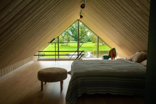 a bedroom with a bed and a large window at Māja Klusumā in Jaunķempji