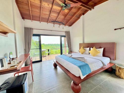 a bedroom with a large bed with a desk and a window at PIDA COFFEE FARM LODGE in Phumĭ Pu Pal