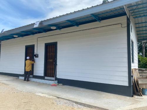 a man standing in the doorway of a white building at DorESA GUESTHOUSE in Machang