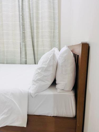 a bed with white sheets and pillows on it at Modern City Escape Near MOA and Airport with Balcony and Fast WiFi in Manila