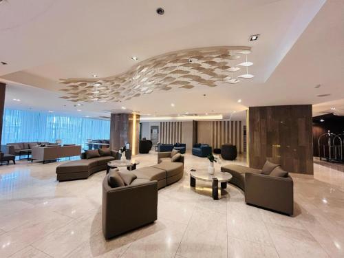 a large lobby with couches and chairs and tables at Modern City Escape Near MOA and Airport with Balcony and Fast WiFi in Manila