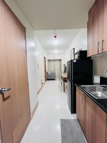 a kitchen with a black refrigerator and a table at Modern City Escape Near MOA and Airport with Balcony and Fast WiFi in Manila