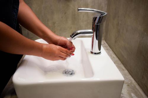a woman is washing her hands under a sink at Casa Emiliana in Valle de Guadalupe