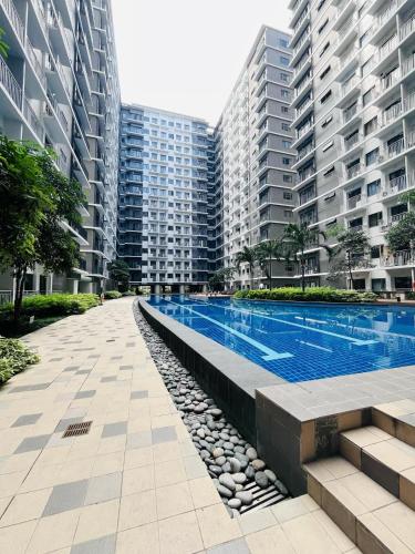 a swimming pool in a city with tall buildings at Modern City Escape Near MOA and Airport with Balcony and Fast WiFi in Manila