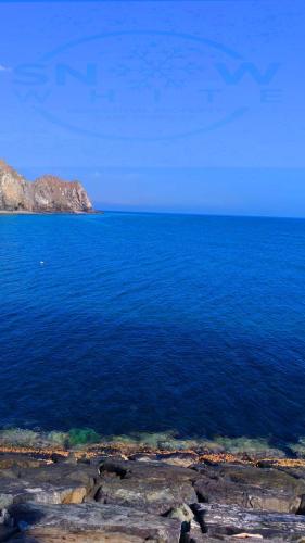 a large body of blue water with mountains in the background at Mina Al Fajer in Rūl Ḑadnā