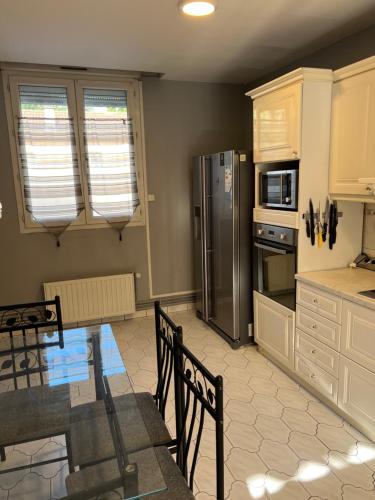 une cuisine avec une table et un réfrigérateur en acier inoxydable dans l'établissement Maison, Proxi Proximité campus, INSA doua centre Villeurbanne, à Villeurbanne