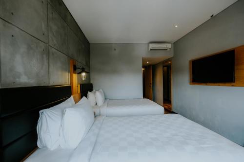 two beds in a room with a tv on the wall at Ayaartta Hotel Malioboro in Yogyakarta