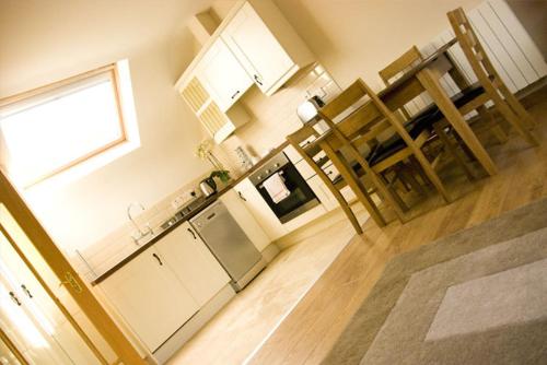 La cuisine est équipée de placards blancs et d'un four avec plaques de cuisson. dans l'établissement Courtyard Loft, à Armagh