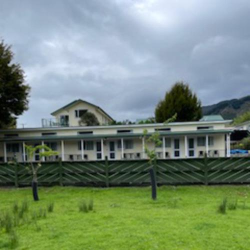 a large white house with a fence in a field at Mataki Motel in Murchison