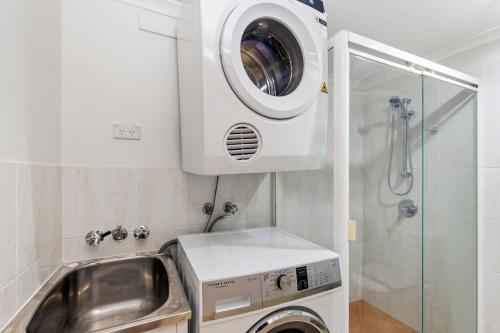a washing machine and a sink in a bathroom at Home-like Garden Apartment in Brisbane
