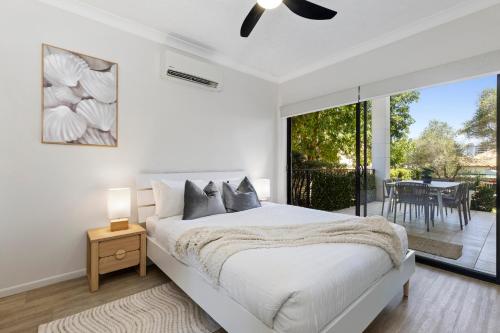 a white bedroom with a bed and a balcony at Home-like Garden Apartment in Brisbane