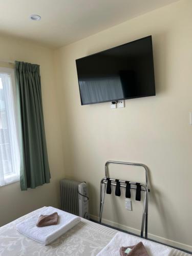 a bedroom with a bed and a flat screen tv on the wall at Mataki Motel in Murchison