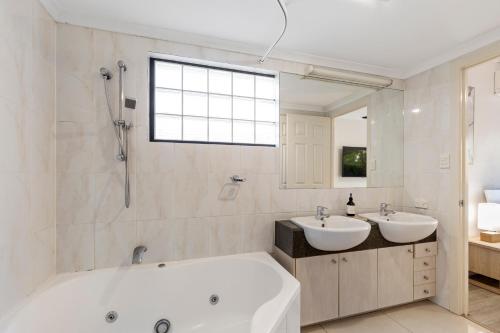 a bathroom with two sinks and a bath tub at Home-like Garden Apartment in Brisbane