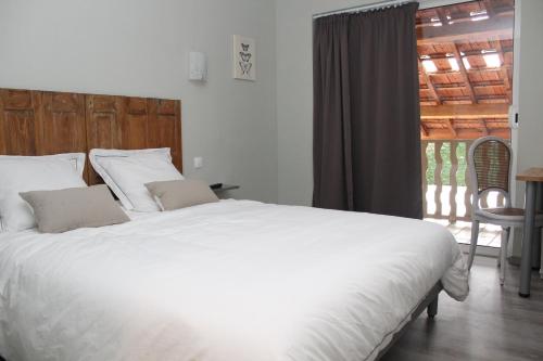 Un dormitorio con una gran cama blanca y una ventana en Sous Le Figuier en Saint-Siméon-de-Bressieux