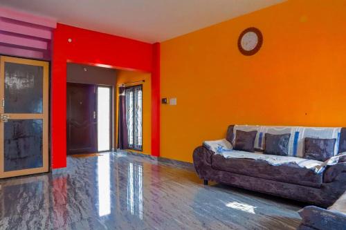 a living room with a couch and an orange wall at Lakeside Home Stay Villa in Yelagiri