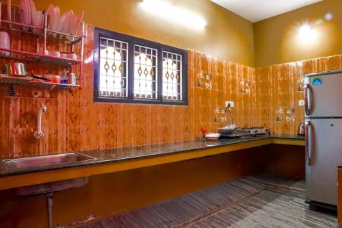 a kitchen with wooden walls and a counter and a refrigerator at Lakeside Home Stay Villa in Yelagiri