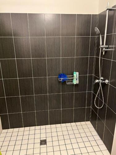 La salle de bains est pourvue d'une douche et d'un mur en carrelage. dans l'établissement Appartement 2 Chambres avec Terrasse, à Clermont-Ferrand