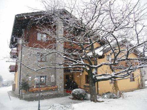 a snow covered house with a tree in front of it at La Vigne de Papagran in Aosta