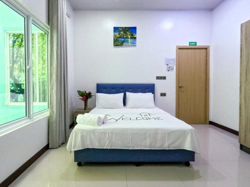 a bedroom with a blue bed and a window at Thooru stay in Kelaa
