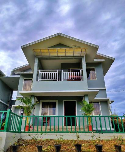 a large house with a balcony with palm trees at The Autumn by Maat Hotels in Vagamon