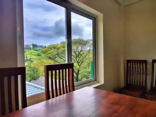 a dining room with a table and a large window at The Autumn by Maat Hotels in Vagamon