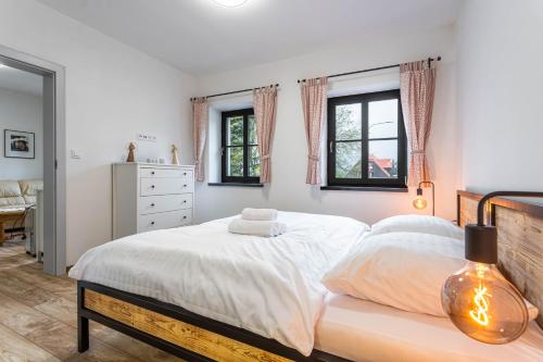 Un dormitorio con una cama con sábanas blancas y ventanas. en Apartmány Quattro, en Loucná pod Klínovcem