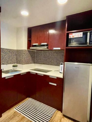 a kitchen with wooden cabinets and a stainless steel refrigerator at FAINA Homestay SCSP Minggarden Resident Kota Kinabalu in Kota Kinabalu