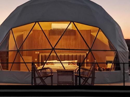 a tent with chairs and a bed in it at WADI RUM STAR WARS CAMP in Wadi Rum