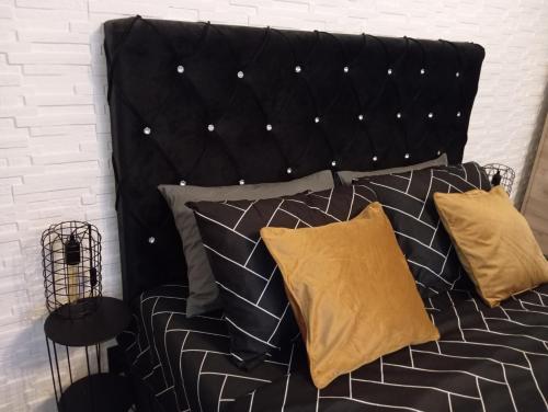 a bed with a black headboard and two pillows at Black Diamond Lux - deluxe riverside apartment in Senta