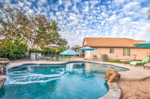a swimming pool with blue umbrellas and a house at Route 66 Oasis in Downtown Gilbert with Heated Pool & Mini Golf in Gilbert