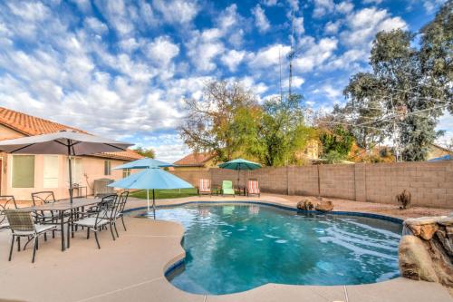a swimming pool with a table and chairs and umbrellas at Route 66 Oasis in Downtown Gilbert with Heated Pool & Mini Golf in Gilbert