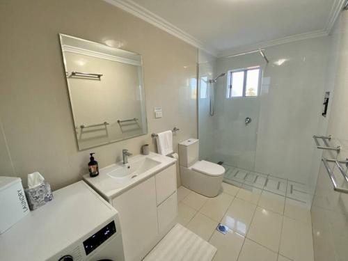 a white bathroom with a sink and a toilet at Palm Terrace Kiama in Kiama