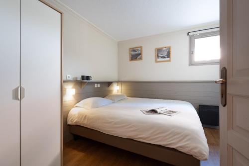 a bedroom with a bed with white sheets and a window at Appartement 6 8 personnes, balcon vue montagne, ski aux pieds in Val Thorens