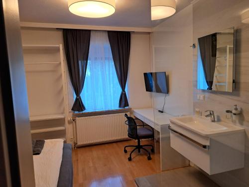 a bathroom with a sink and a desk and a window at Flataid Gästehaus Graschi - gutes und günsiges Einzelzimmer - Steinbergstraße in Graz