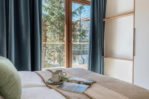 a bedroom with a bed with a window and a tray with a book at Apres Ski Bachleda - LoftAffair Collection in Zakopane