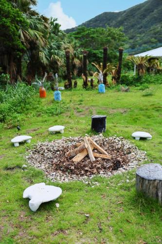 a garden with a pile of wood in the grass at 泊まれるアートミュージアム 琉球ヴィラ in Tatsugo