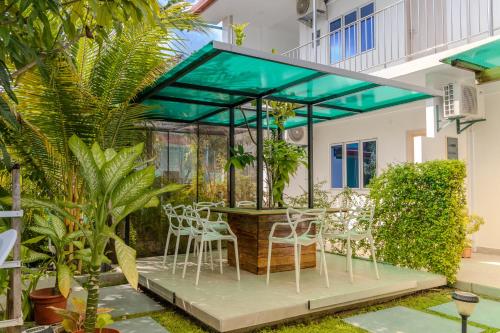 a glass house with white chairs and a table at Thooru stay in Kelaa