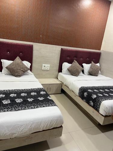 two beds sitting next to each other in a room at Hotel KF Residency in Mumbai