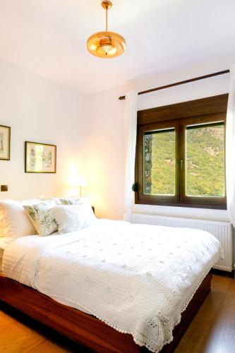 a white bedroom with a bed and a window at Villa Natsi in Aspróyia