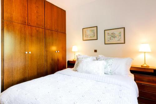 a bedroom with a large white bed and wooden cabinets at Villa Natsi in Aspróyia