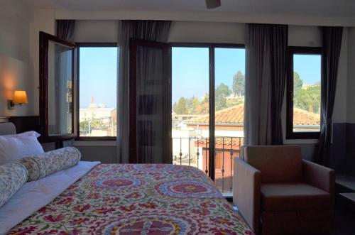 a bedroom with a bed and a balcony with windows at Ayasoluk Hotel & Restaurant in Selcuk